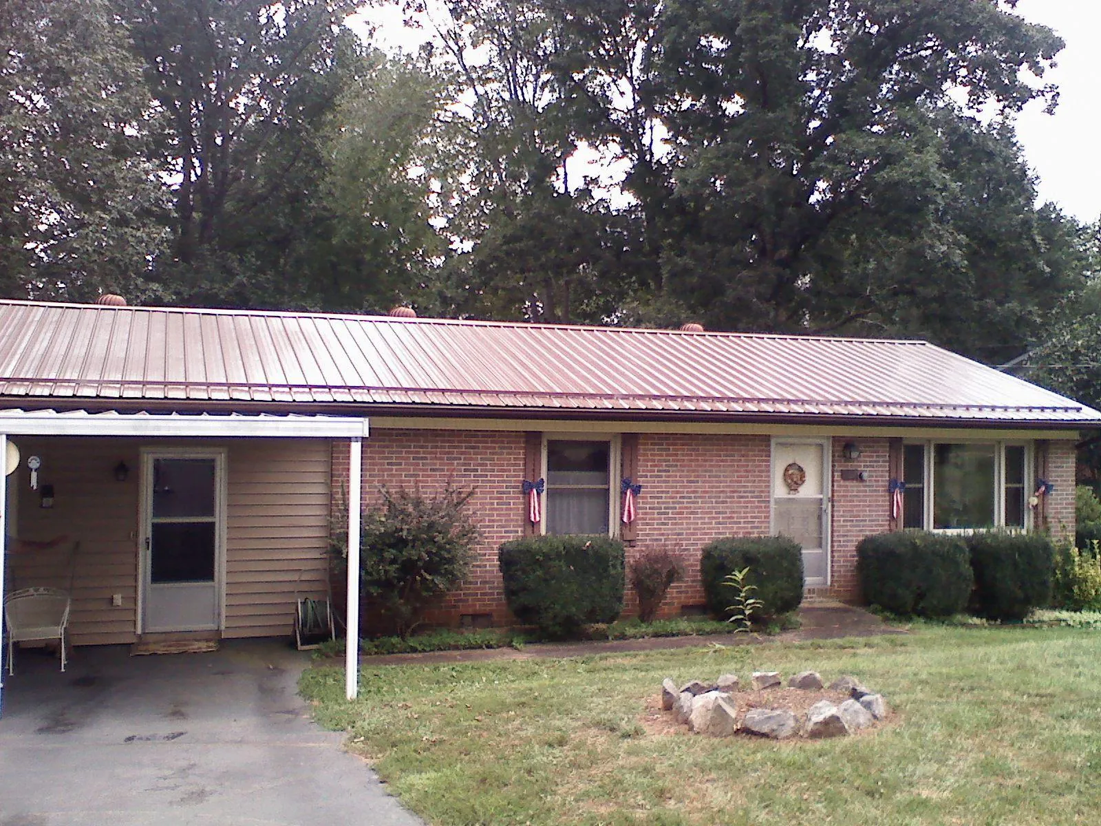 Bronze metal roof and carport on a brick ranch home — Roof Repair work by our crew in Walton